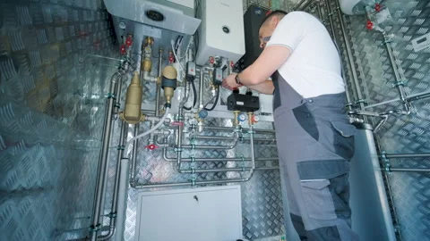 HVAC Technician Adjusting Heat Pump and Boiler System in Modern Mechanical Room Stock Footage 340112451
