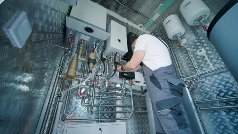 HVAC Technician Adjusting Heat Pump and Boiler System in Modern Mechanical Room Stock Footage 340112472