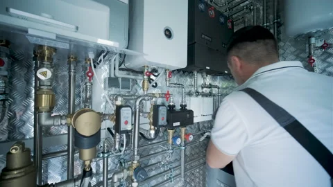 HVAC Technician Adjusting Heat Pump and Boiler System in Modern Mechanical Room Stock Footage 340112516