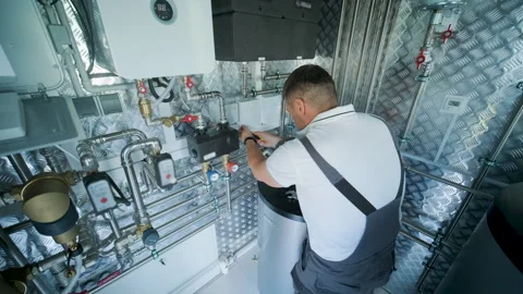 HVAC Technician Adjusting Heat Pump and Boiler System in Modern Mechanical Room Stock Footage 340112602