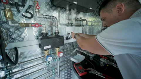 HVAC Technician Adjusting Heat Pump and Boiler System in Modern Mechanical Room Stock Footage 340112615