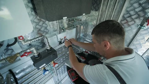 HVAC Technician Adjusting Heat Pump and Boiler System in Modern Mechanical Room Stock Footage 340112649