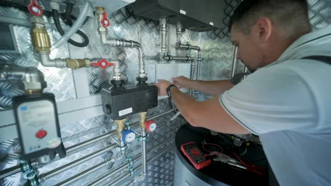 HVAC Technician Adjusting Heat Pump and Boiler System in Modern Mechanical Room Stock Footage 340112656