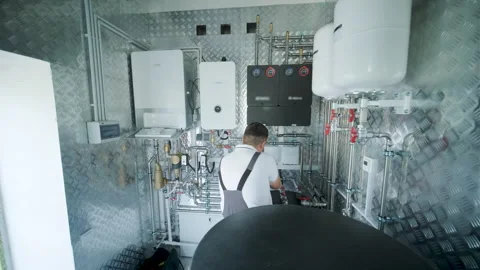 HVAC Technician Adjusting Heat Pump and Boiler System in Modern Mechanical Room Stock Footage 340112689