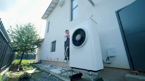 HVAC technician on a ladder installing a large outdoor heat pump unit Stock Footage 340112890