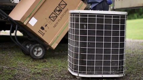 HVAC technicians wheel in a new air conditioner while old one sits unused  Vidéo 75872272