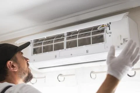 Hvac worker performing air conditioner maintenance, inspecting a dirty filt.. Stock-Fotos