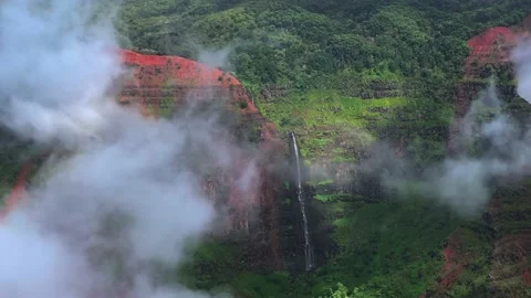 Hwaii Waterfall in the clouds with green forest and red canyon Stock Footage 166461528