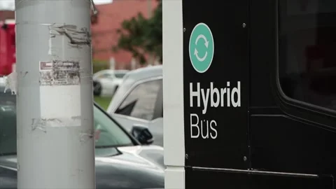 Hybrid bus writing text caption words printed on bus stopped at light Stock-Footage 247753507