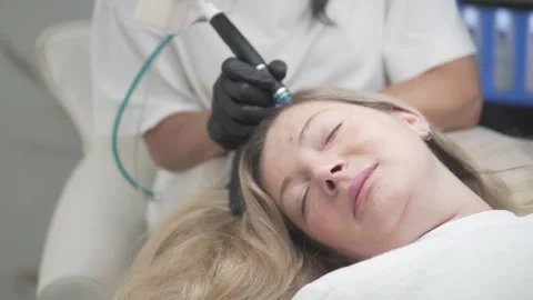 HydraFacial Keravive treatment in progress on a smiling woman with long blonde Stock Footage 311874167