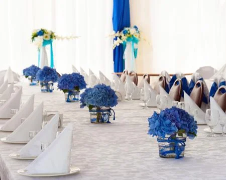 Hydrangea flowers in vases on festive table with cutlery. Stock Photos