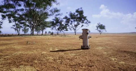 Hydrant stands alone in dry landscape under clear blue sky Stock Illustration