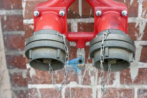 Hydrant with two taps for quick collection of water on a brick wall. 写真素材