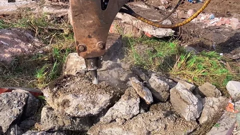 A hydraulic hammer breaks a concrete block while clearing a rubble and clearing Stock Footage 265033914