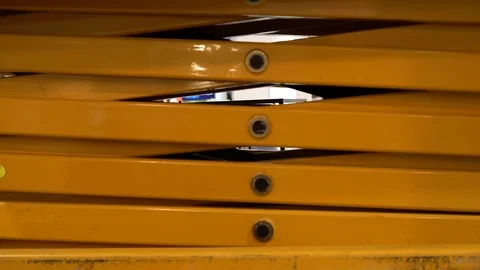 Hydraulic scissor platform closing down. Close up of yellow scissors lift Video stock 124634462