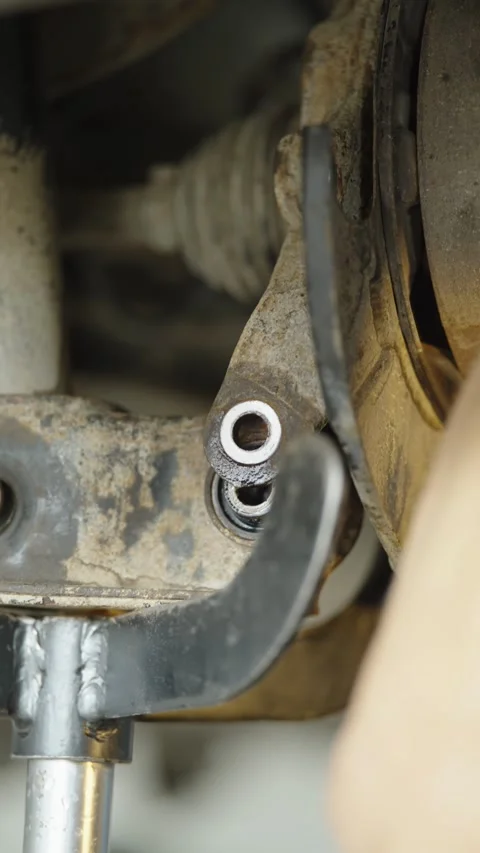 Hydraulic transmission jack supporting a dirty car rear suspension arm Stock Footage 337568254