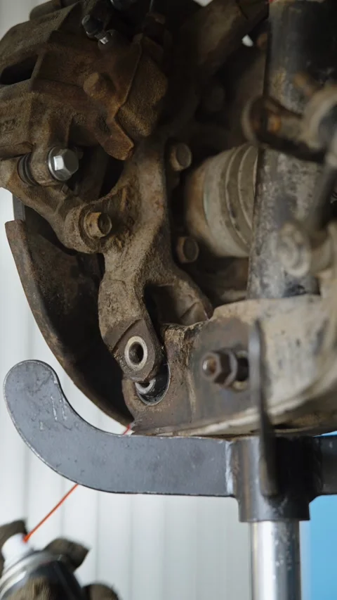 Hydraulic transmission jack supporting a dirty car rear suspension arm Stock Footage 337568456
