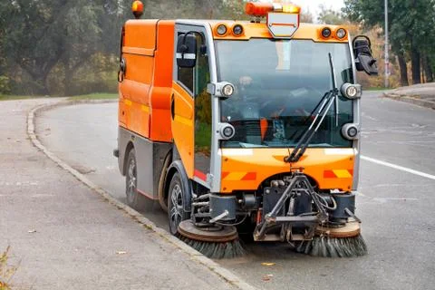 A hydraulically powered road sweeper sweeps the street. Stock Photos