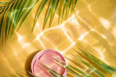 Hydro gel eye patch on yellow background with palm leaves and water highlight Stock Photos