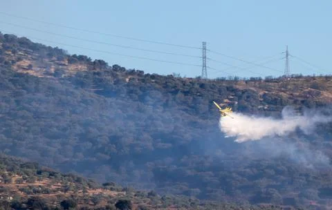 Hydro plane throwing water for fire extinction with deep blue sky on background Stock Photos