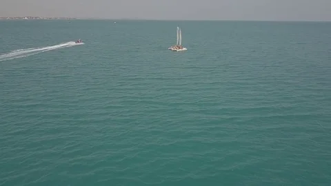 Hydrocycle rides around the catamaran in the Black sea viewing from drone in Stock Footage 77707730