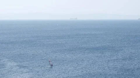 Hydrofoil windsurfer rides waves at high speed on the open Adriatic Sea Stock Footage 344765380