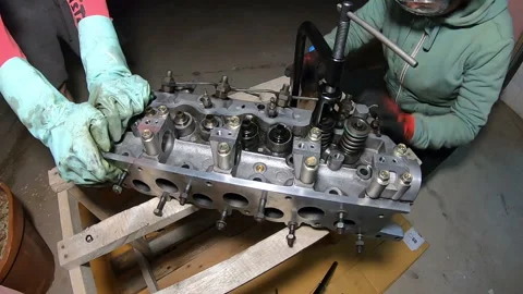 Hyper lapse of two people removing the springs from a cylinder head Video stock 171085211