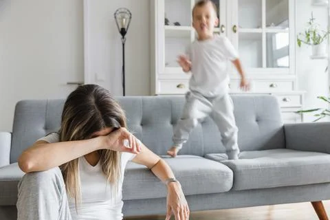 Hyperactive child and his tired mother at home Foto stock