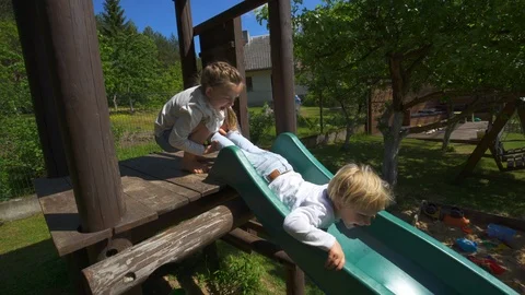 Hyperactive children slide down on playground. Kid play and laugh. Handheld Stock Footage 109553386