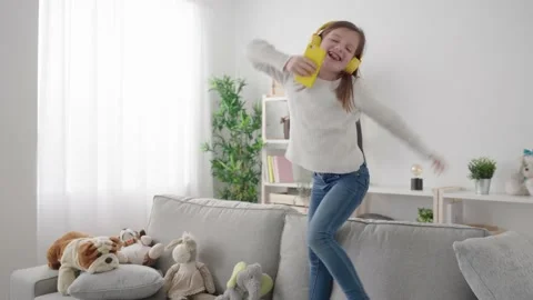 Hyperactive girl jumping and dancing on sofa Stock Footage 235309049