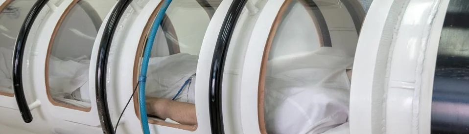 A hyperbaric chamber with a man lying inside. Treatment in an oxygen capsule. Stock Photos