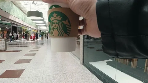 Hyperlapse shot of a man holding a recyclable coffee cup with the Starbucks logo Stock Footage 131611319