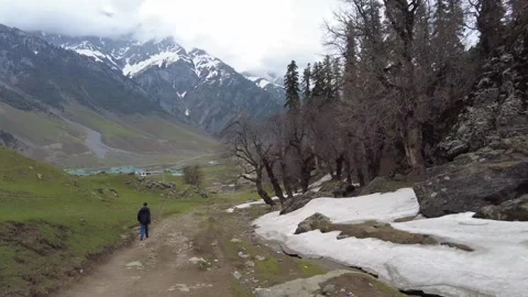HyperLapse Stroll of a man walking at hill near snow beds and trees in Kashmir Stock Footage 255192701