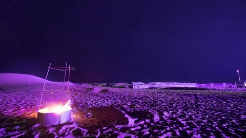 Hyperlapse, timelapse of stars in the night sky over the desert and the bonfire. Stockbeeldmateriaal 84222748