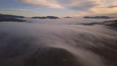 Hypnotic aerial timelapse footage of clouds rolling over hills into ocean. Stock Footage