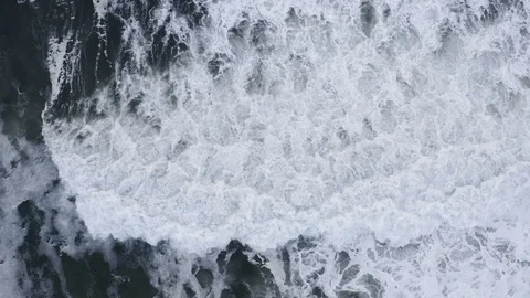 Hypnotic slow-motion waves crash to shore after storm, top down aerial Stock Footage 112703318