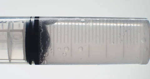 Hypodermic Needle Barrel with Clear Liquid Pushed Through Stock Footage 284213013