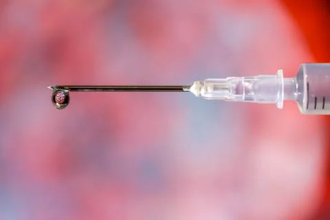 Hypodermic needle dripping fluid over a red and grey out of focus background Stock Photos