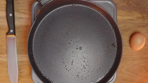 I am getting ready to cook using a wooden spoon, a frying pan, and an egg for Stock Footage 306014060