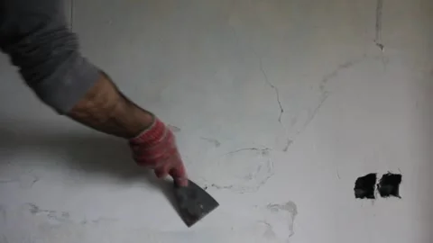 I am scraping the wall with a spatula before painting it white Stock Footage 252233941