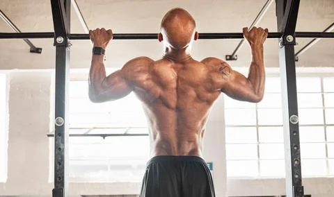 I can do one more. a man completing pull ups in his gym. Stock Photos