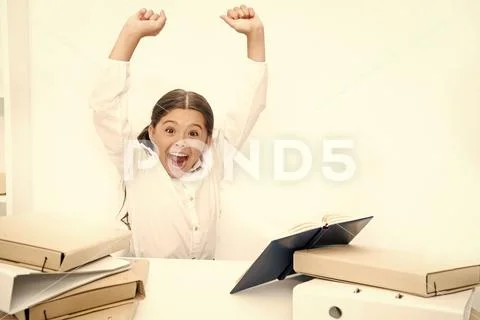 I did it. Happy girl keeping her arms raised at desk. Schoolgirl reading school Stock Photos