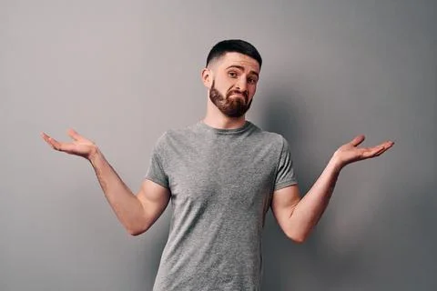 I do not know! A young man dressed in a gray T-shirt on a background of a gra Stock Photos