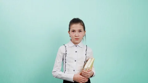 I dont hear you talking. Portrait of a young girl with books in hand, putting Video stock 126034097