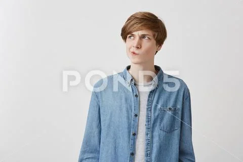 I don't know. Doubtful caucasian young male wearing denim shirt, pouting lips Stock Photos