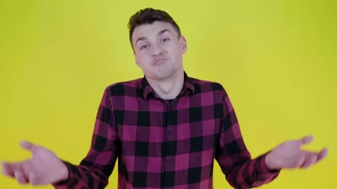 I dont know. Man in a pink plaid shirt raises his hands on a yellow background Stock Footage 131610293