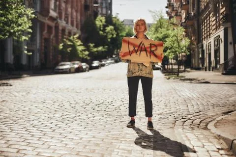 I hate war Full length of young confident female holding a signboard with word Stock Photos