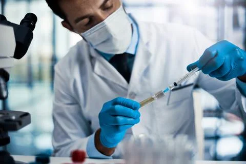 I have to put just enough. a young male scientist working in a lab. Stock Photos