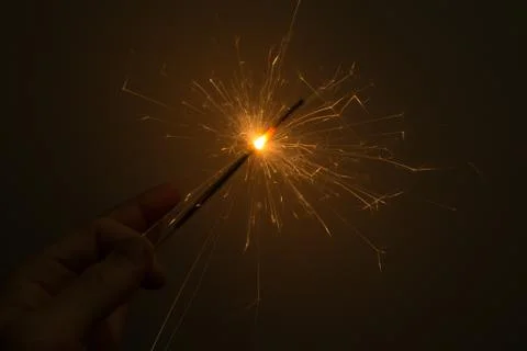 I hold a sparkler, which sparkles beautifully in different directions. Stock Photos