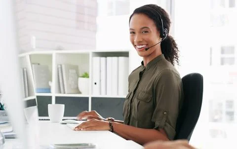 I know just the answer. a young woman using a computer and headset in a modern Stock Photos